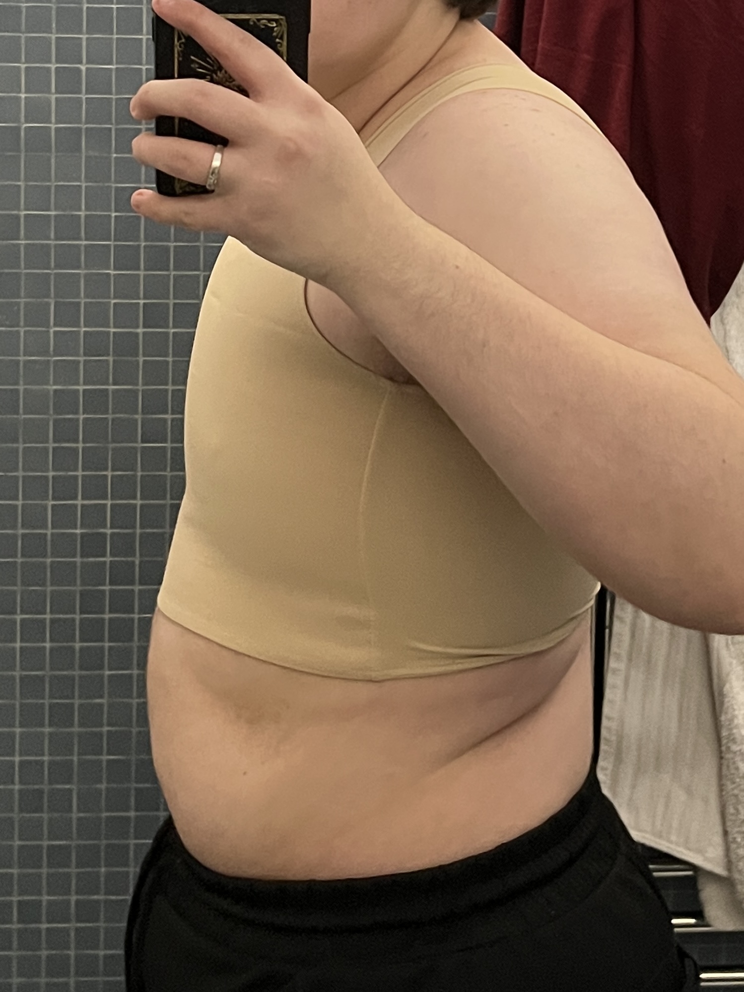 Trans man wearing a tan half binder facing sideways